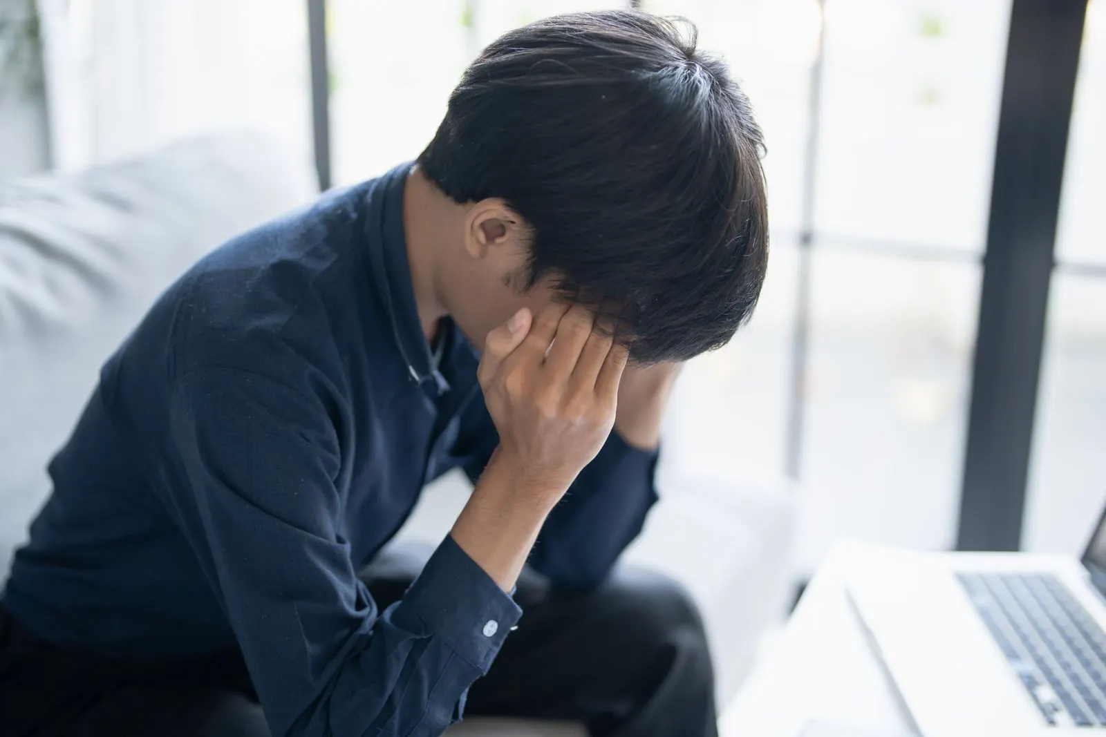 うつむいて頭を抱える人物